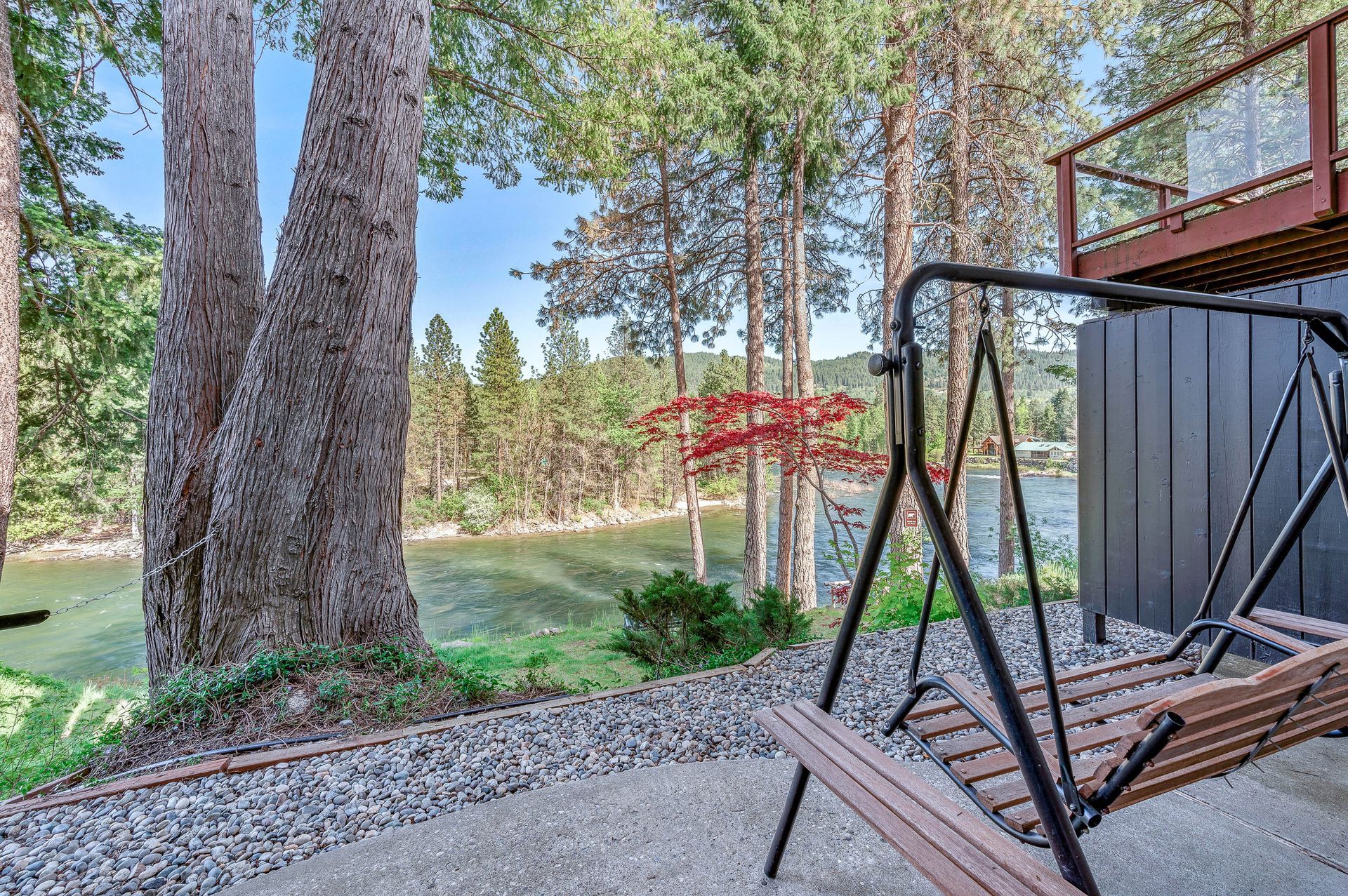 There is a swing set in the backyard of a house with a view of a lake.