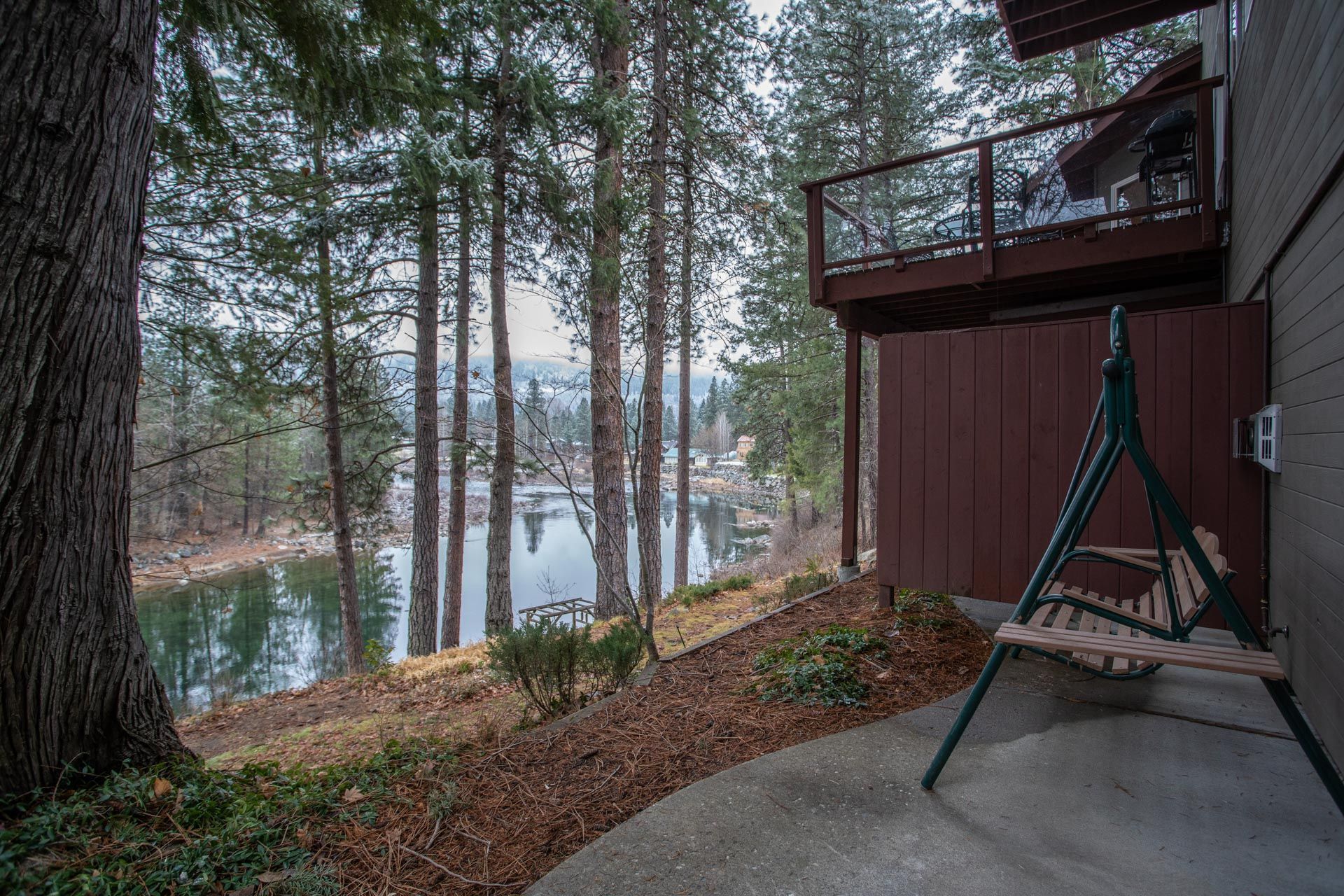 A house with a swing and a view of a lake surrounded by trees.