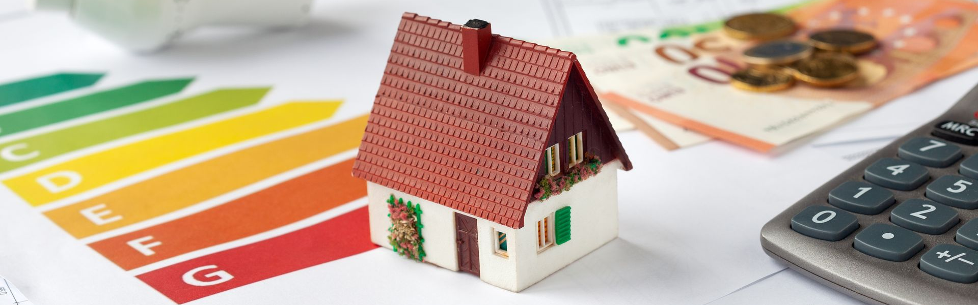Une maison miniature avec une calculatrice et de la monnaie