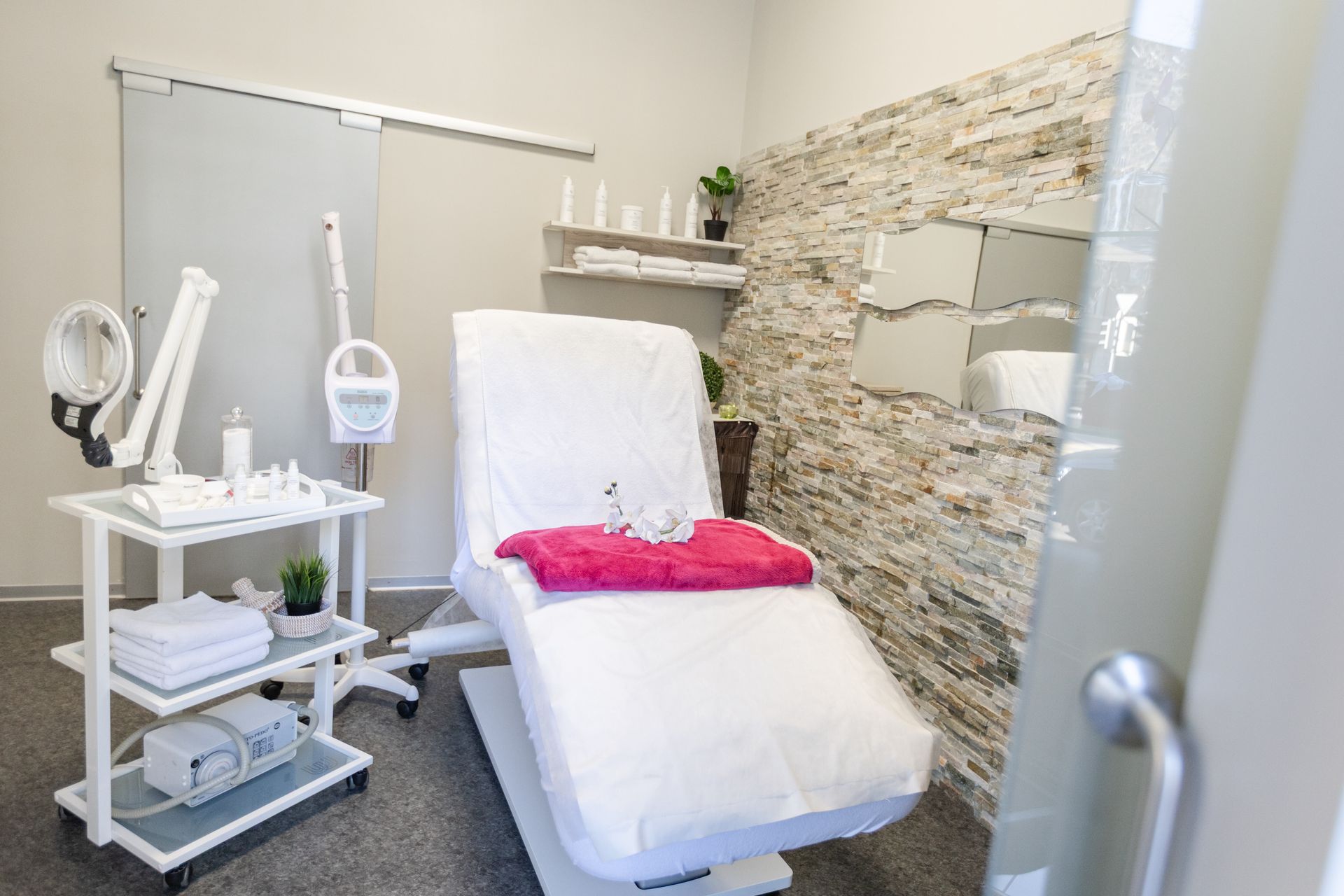 Ein hell erleuchteter Friseursalon mit schwarzen Frisierstühlen, Arbeitsplätzen mit Spiegeln, einem Waschbecken und Topfpflanzen.
