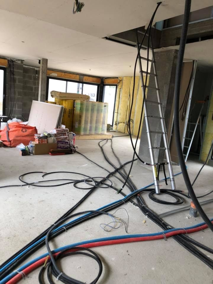 Intérieur d'une maison en travaux avec de nombreux câbles électriques.