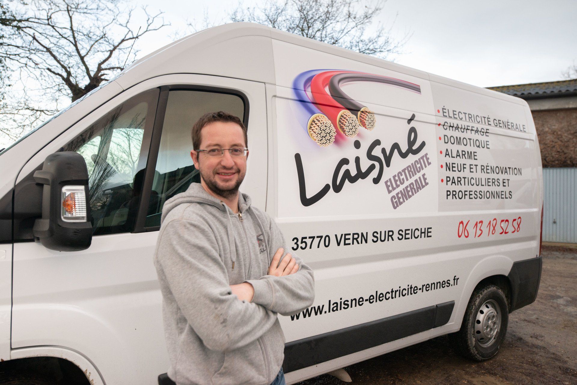 Professionnel qui croise les bras contre un camion d'électricien.