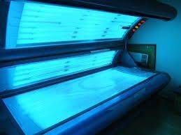 Un lit de bronzage avec des lumières bleues dans une pièce sombre.