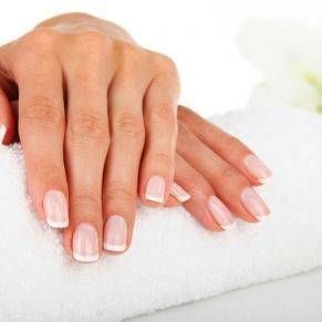 Les mains d'une femme aux ongles roses sont posées sur une serviette blanche.