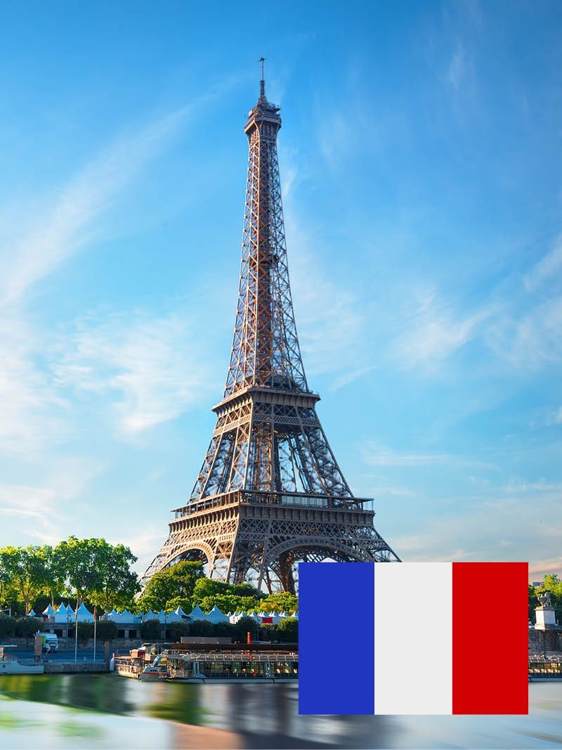 Eiffelturm in Paris mit der französischen Flagge im Vordergrund. Der Turm ragt hoch vor einem strahlend blauen Himmel empor und spiegelt sich im Wasser darunter.