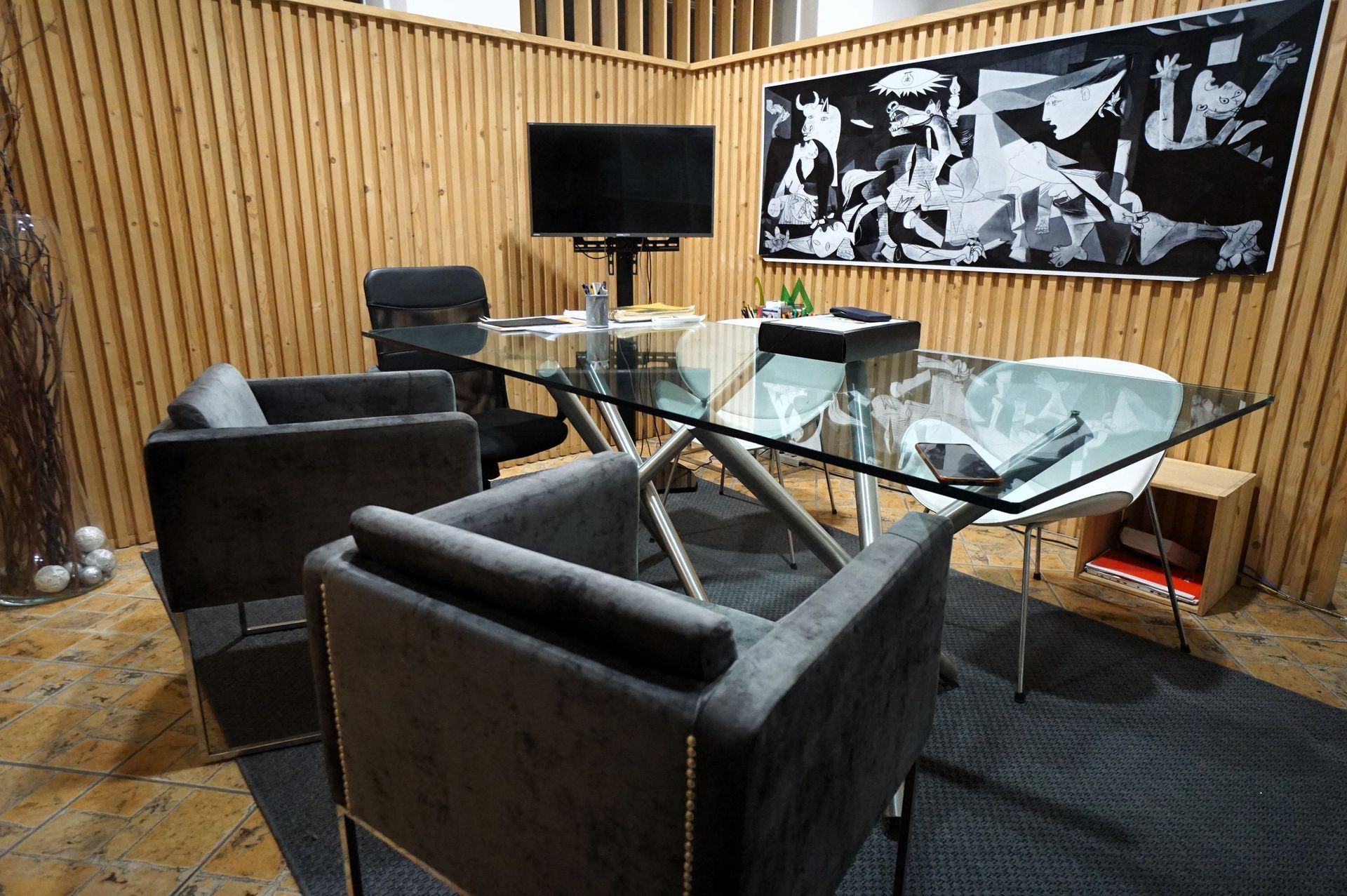 Una sala de conferencias con una mesa de cristal y sillas y un televisor.
