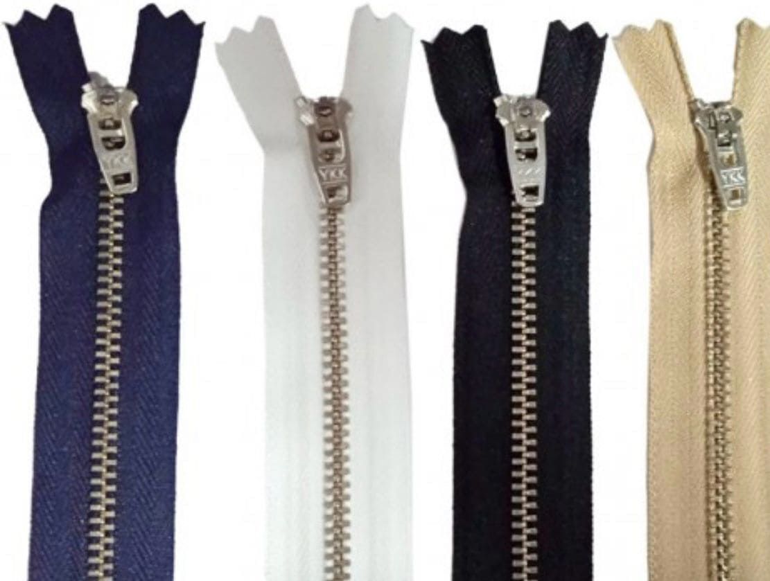 Cuatro cremalleras de diferentes colores están alineadas sobre un fondo blanco.