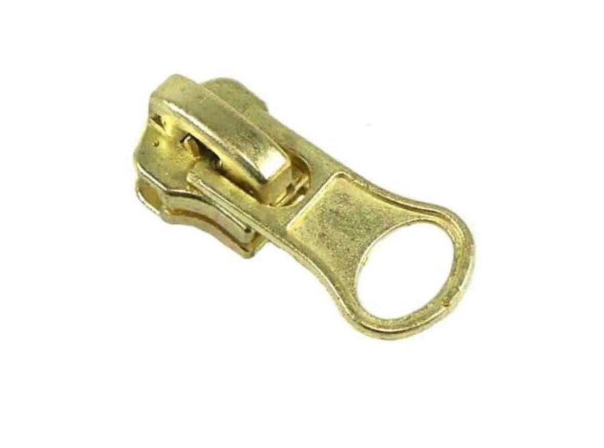 Un primer plano de un tirador de cremallera dorado sobre un fondo blanco.