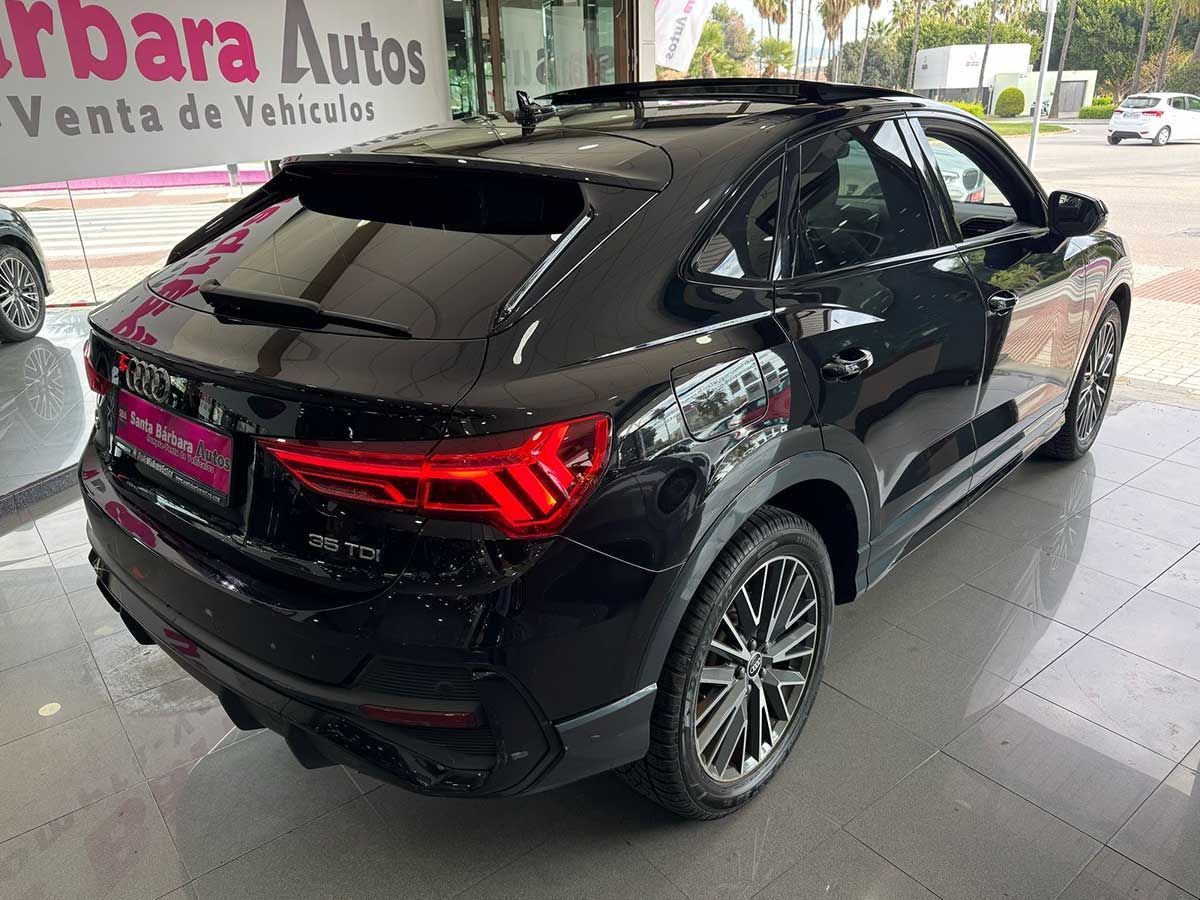 Audi Q3 Sportback negro estacionado en un concesionario de automóviles, mostrando la parte trasera del vehículo.