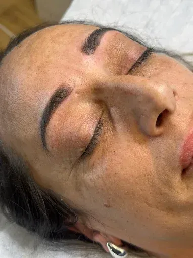 Mano con uñas largas y rosas bien cuidadas y detalles brillantes, apoyada sobre una superficie suave y peluda de color rosa.