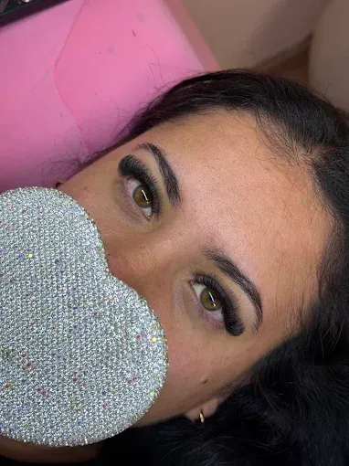 Manicura francesa con puntas blancas y un pequeño detalle de flor blanca sobre uñas nude brillantes.