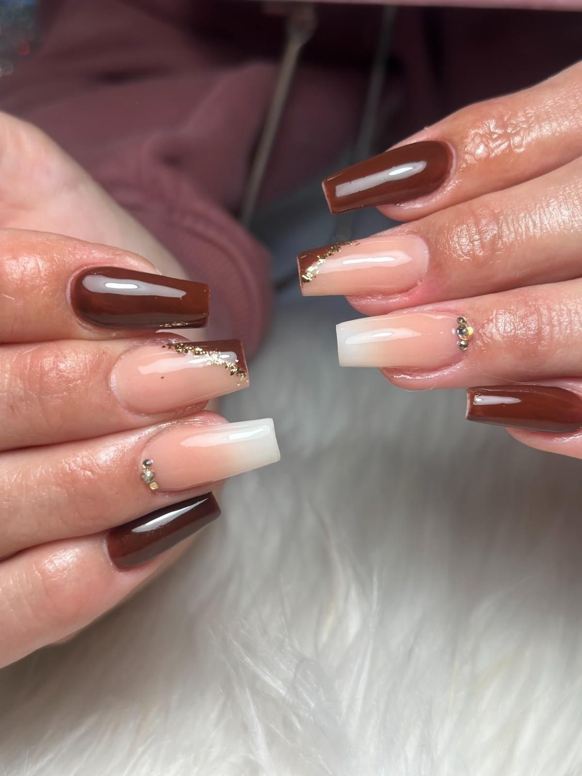 Mano con uñas largas y rosas bien cuidadas y detalles brillantes, apoyada sobre una superficie suave y peluda de color rosa.
