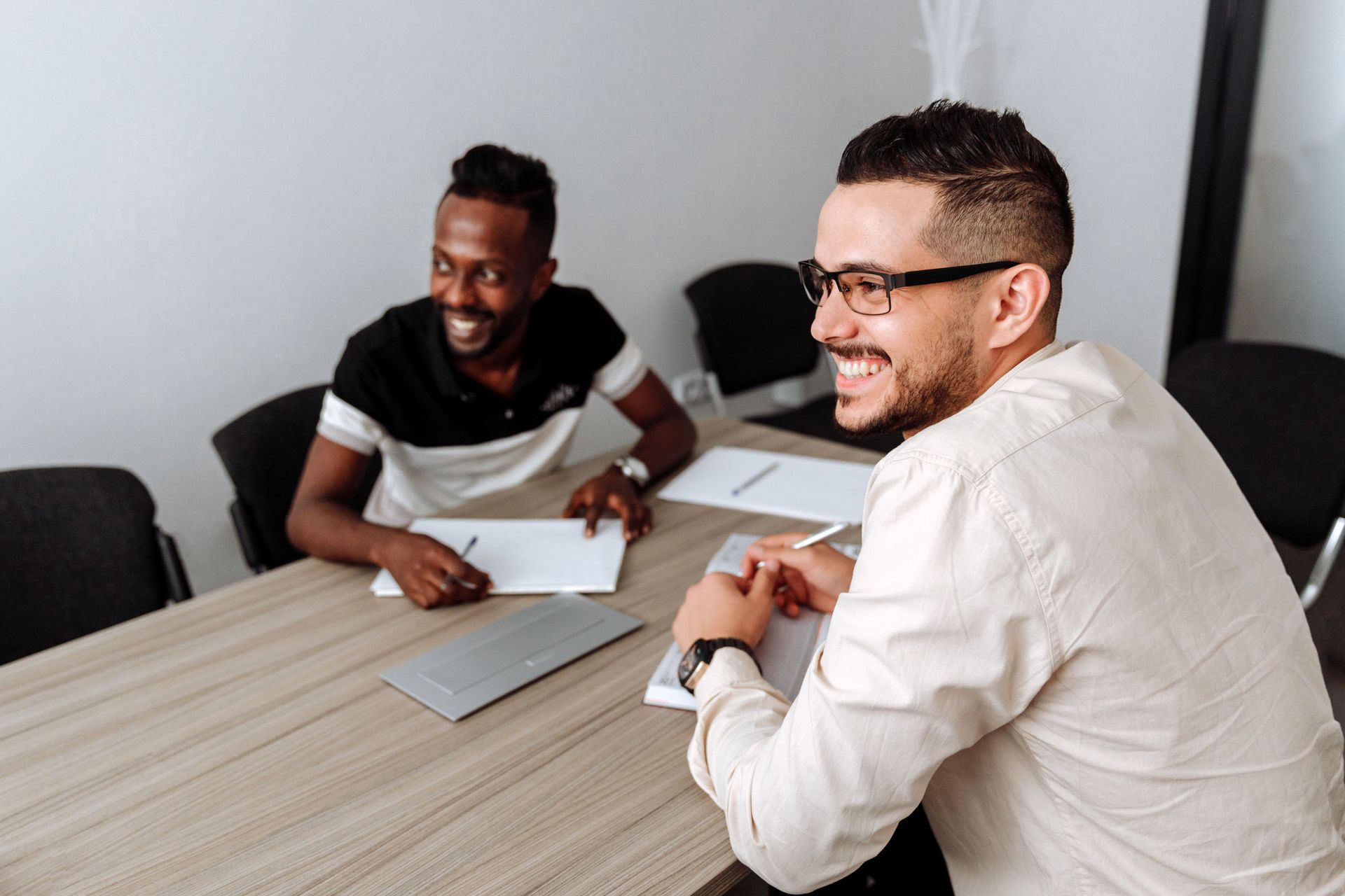 Des personnes collaborent autour d'un ordinateur portable à une table de réunion, leurs mains désignant des documents.