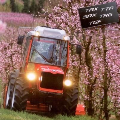 Un tractor rojo conduce por un campo de flores rosas.