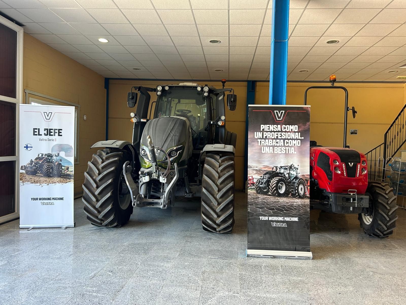 Un tractor está estacionado en una sala de exposición al lado de un cartel.