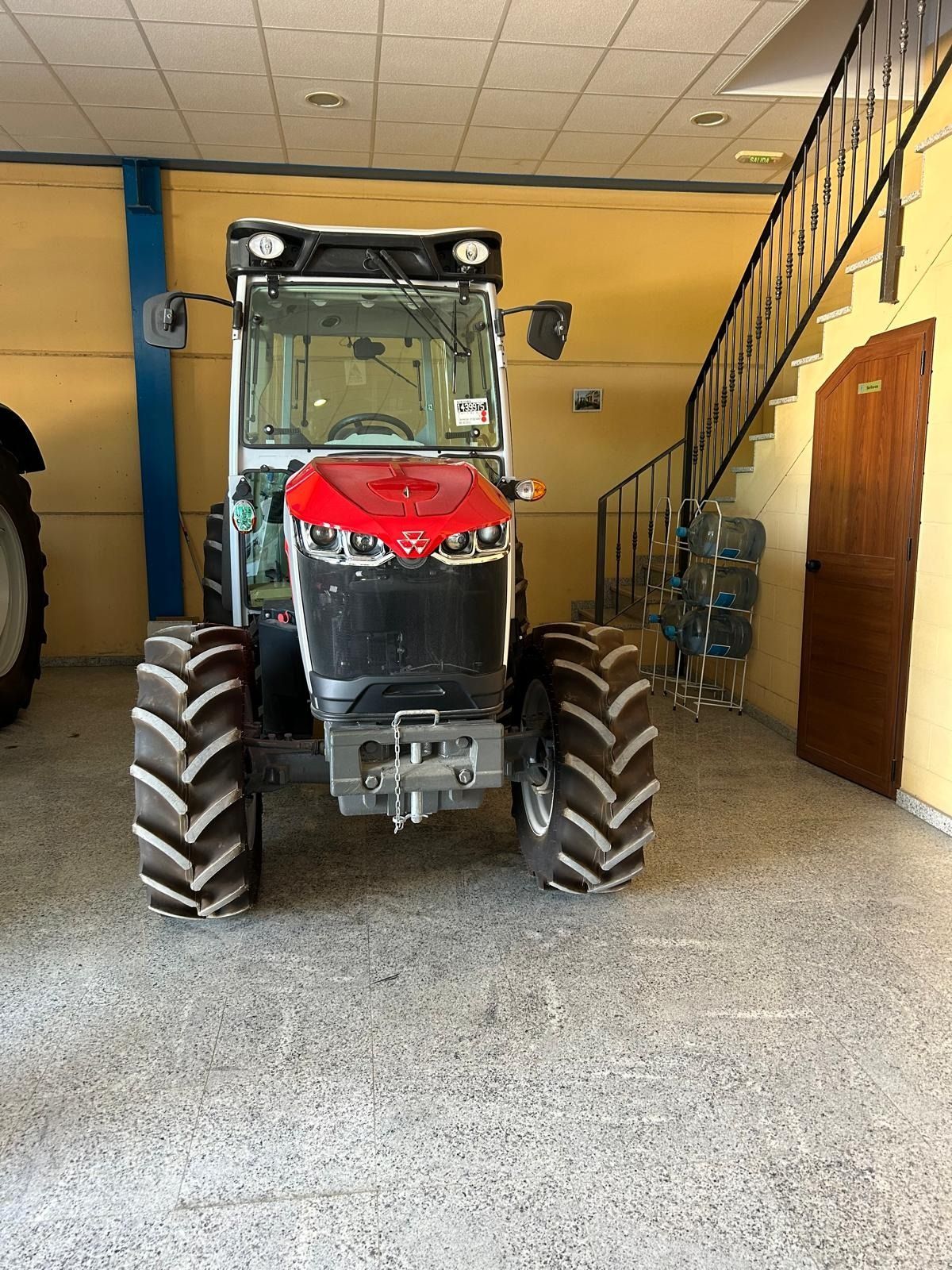 Un tractor rojo y negro está estacionado en un garaje.