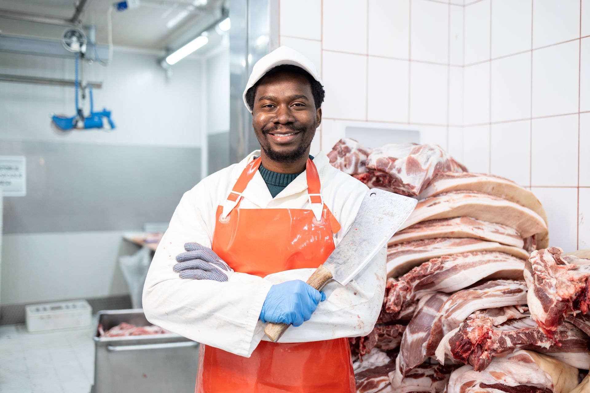 Ein Metzger steht vor einem Stapel Fleisch in einer Metzgerei.