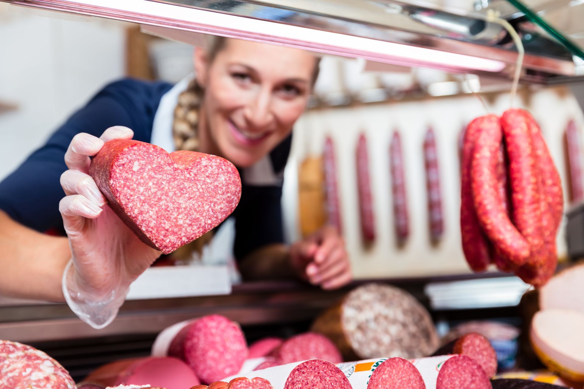 Eine Frau hält ein Stück Salami in Form eines Herzens in der Hand
