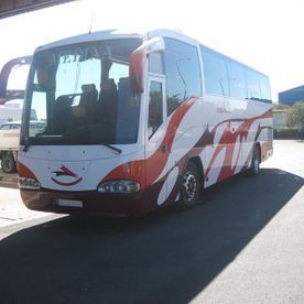 Un autobús rojo y blanco está estacionado al costado de la carretera.