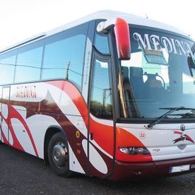 Un autobús rojo y blanco de Medina está estacionado al costado de la carretera.