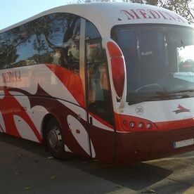 Un autobús rojo y blanco está estacionado al costado de la carretera.