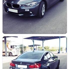 Un BMW Serie 3 está estacionado en un estacionamiento al lado de un camión.