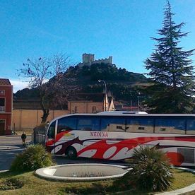 Un autobús rojo y blanco está estacionado frente a un castillo.