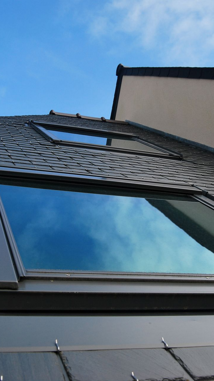 Des fenêtres de toit sur une toiture en ardoise.