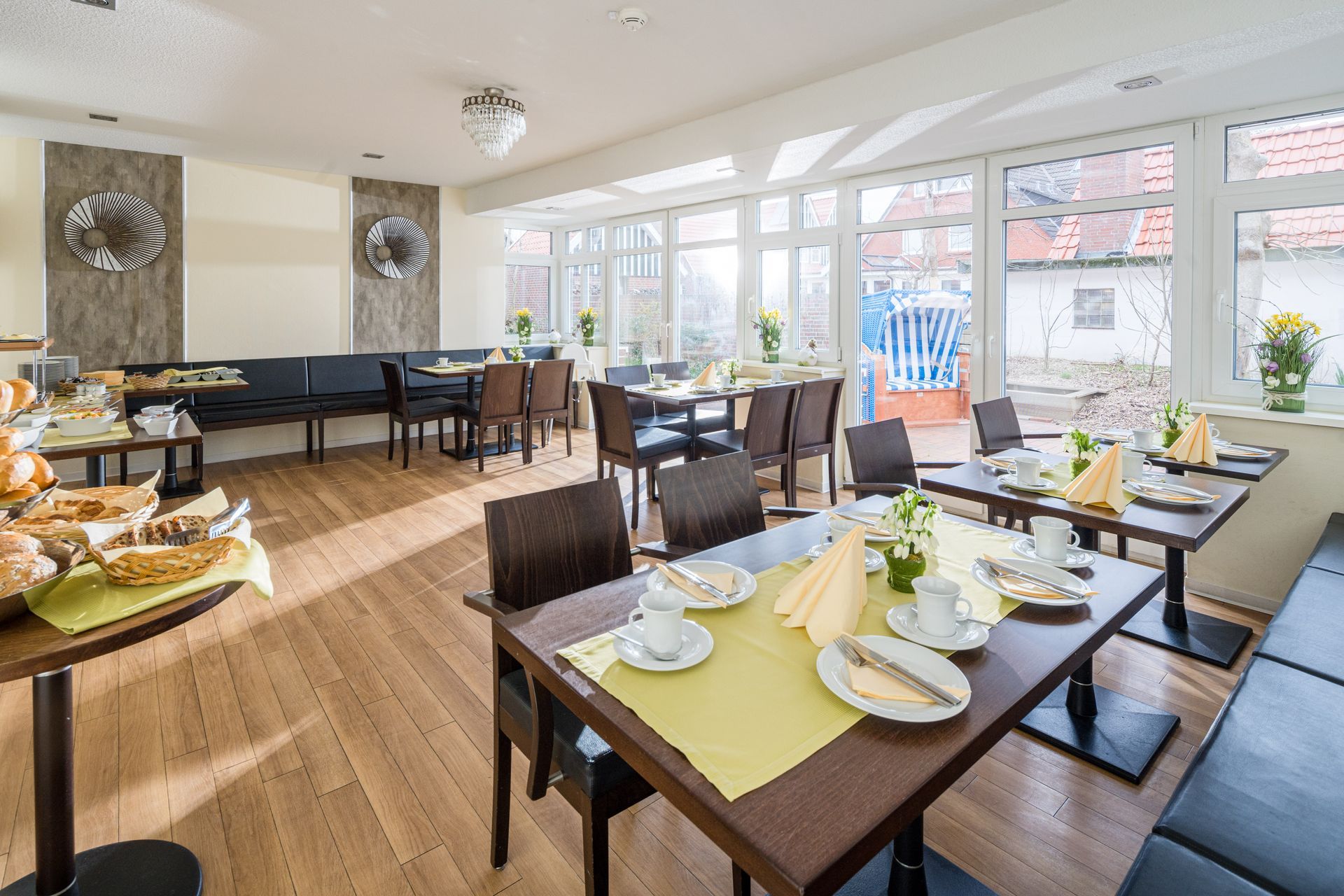 Buffet mit Gebäck, Obst und anderen Frühstücksartikeln in einem gut beleuchteten Raum mit Holzboden.