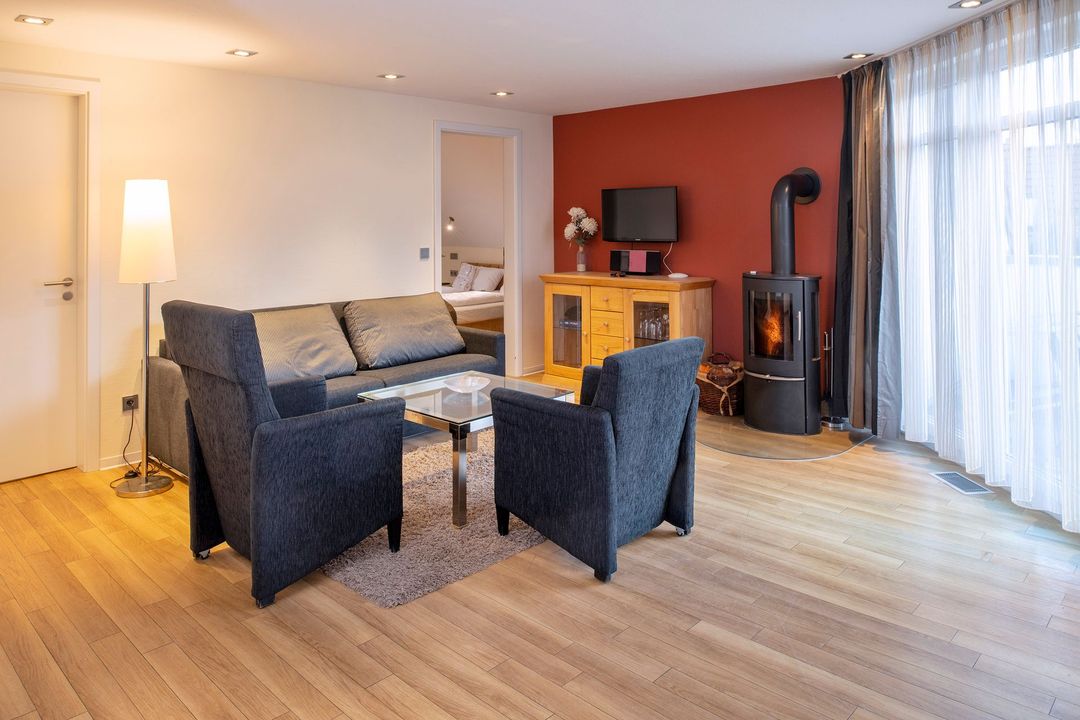 Schlafzimmer mit Bett, Schreibtisch, Balkon und offenen Doppeltüren.
