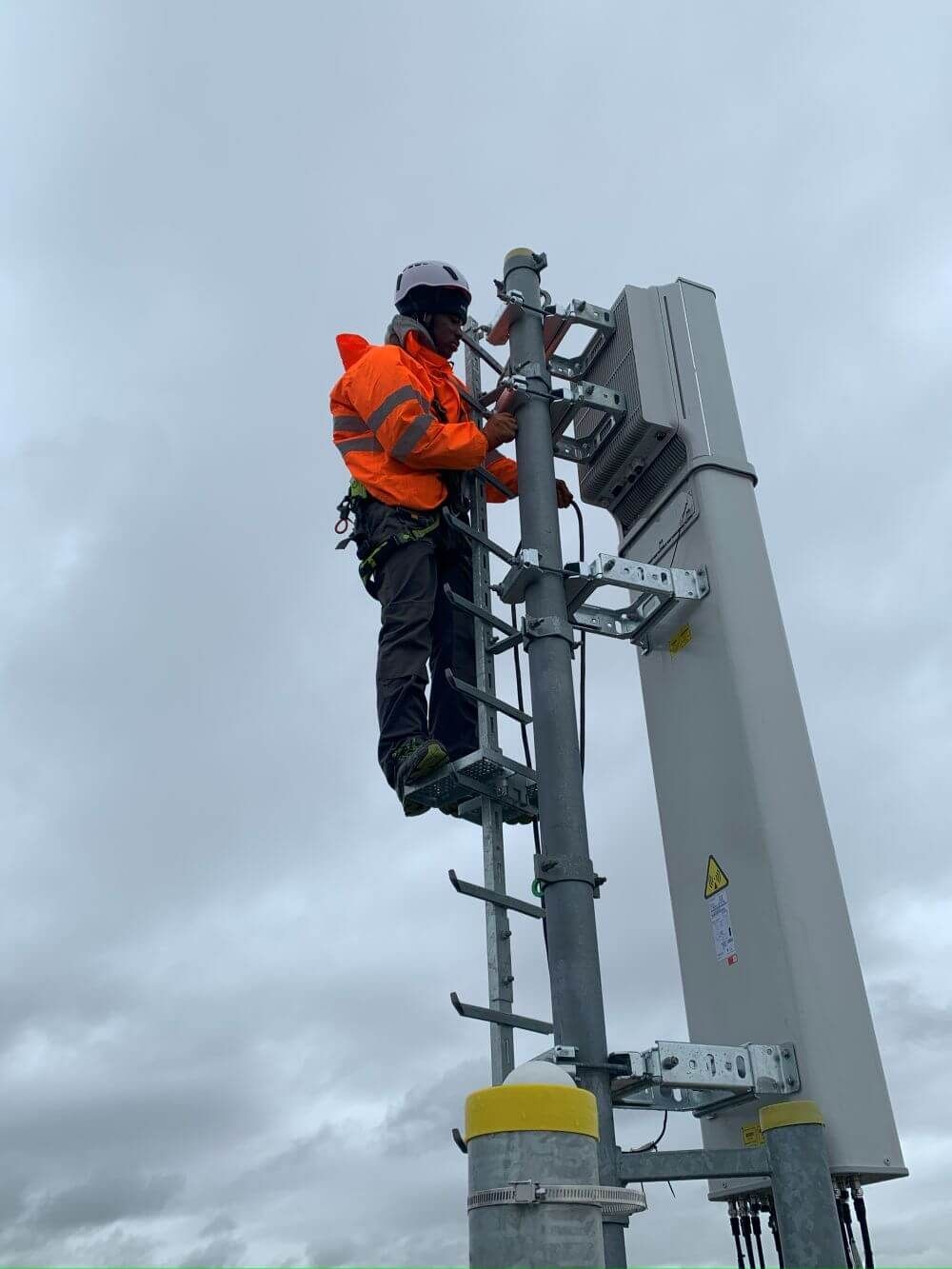 Homme sur une échelle d'un mât électrique pour mise en sécurité.