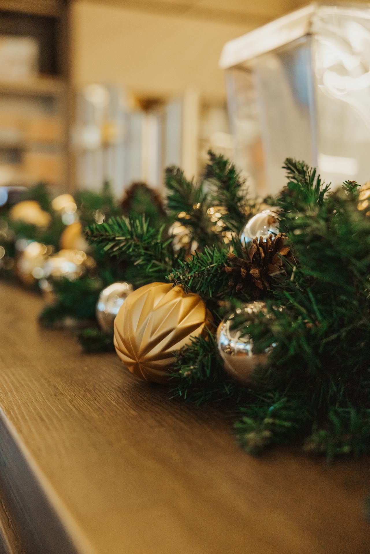 Weihnachtsgirlande mit goldenen und silbernen Ornamenten auf einer Holzoberfläche.