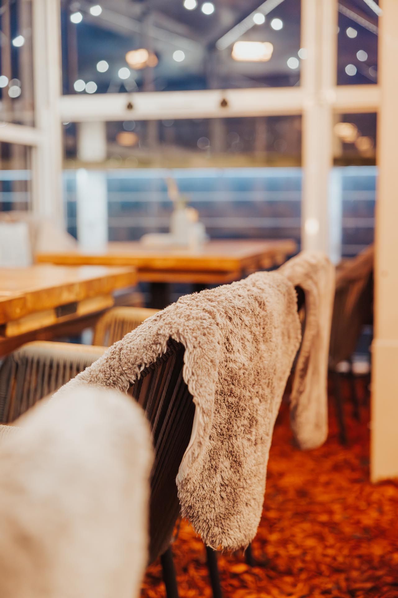 Gemütlicher Essbereich im Innenbereich, Fokus auf einem mit einer flauschigen Decke bedeckten Stuhl.