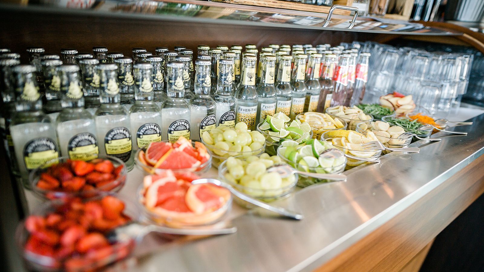 Eine Bar-Ausstellung mit Flaschen, Früchten und Garnituren für Getränke.