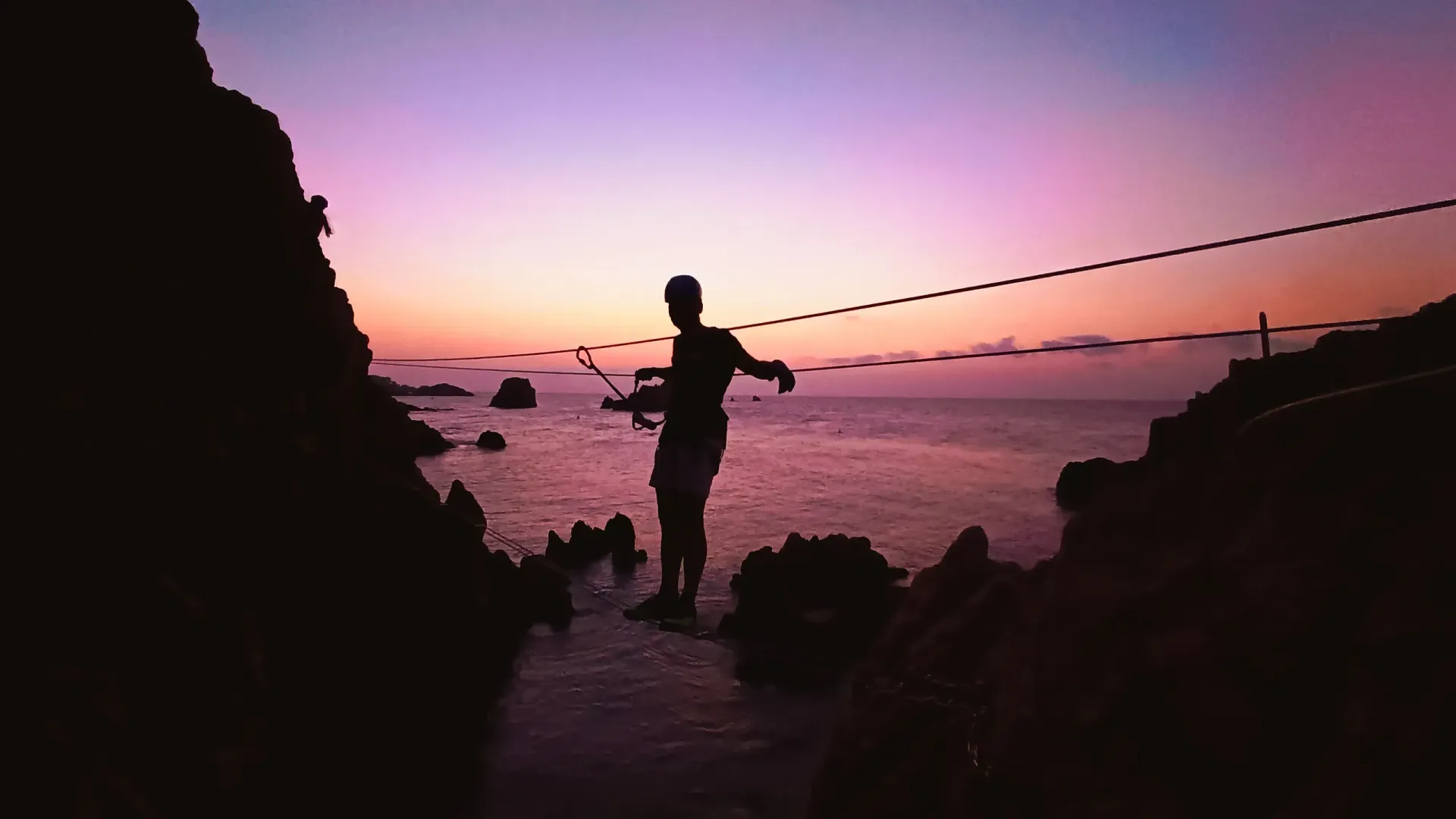 Un hombre está pescando en el océano al atardecer.