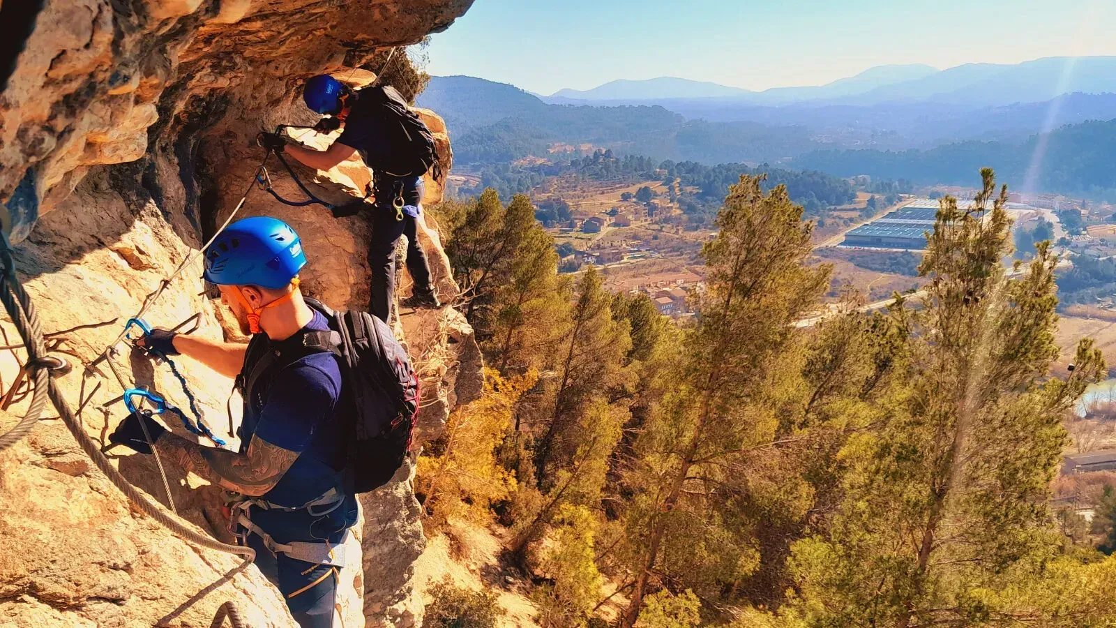 Un hombre con un casco azul está escalando una montaña.