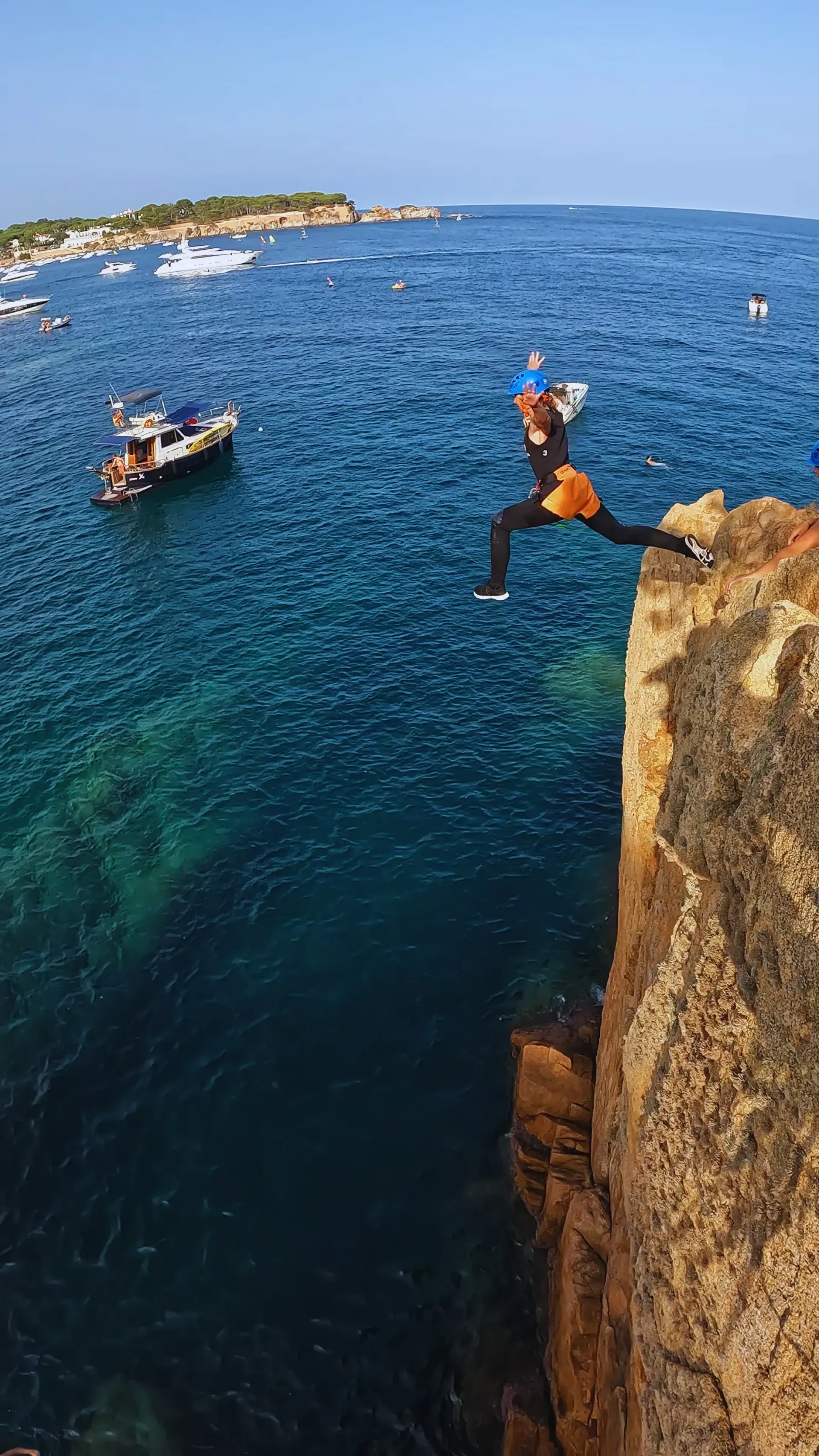 Una persona está saltando desde un acantilado hacia el océano.