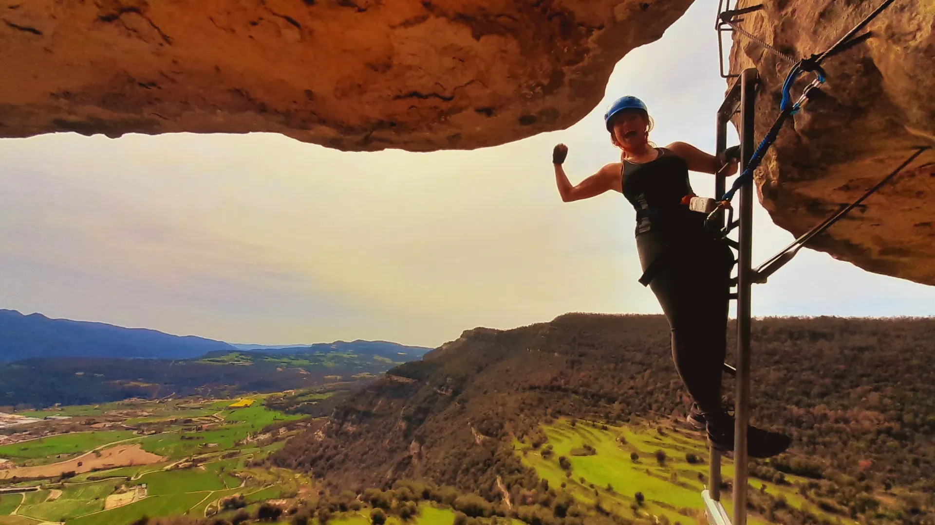 Una mujer está parada en una escalera en lo alto de una roca.