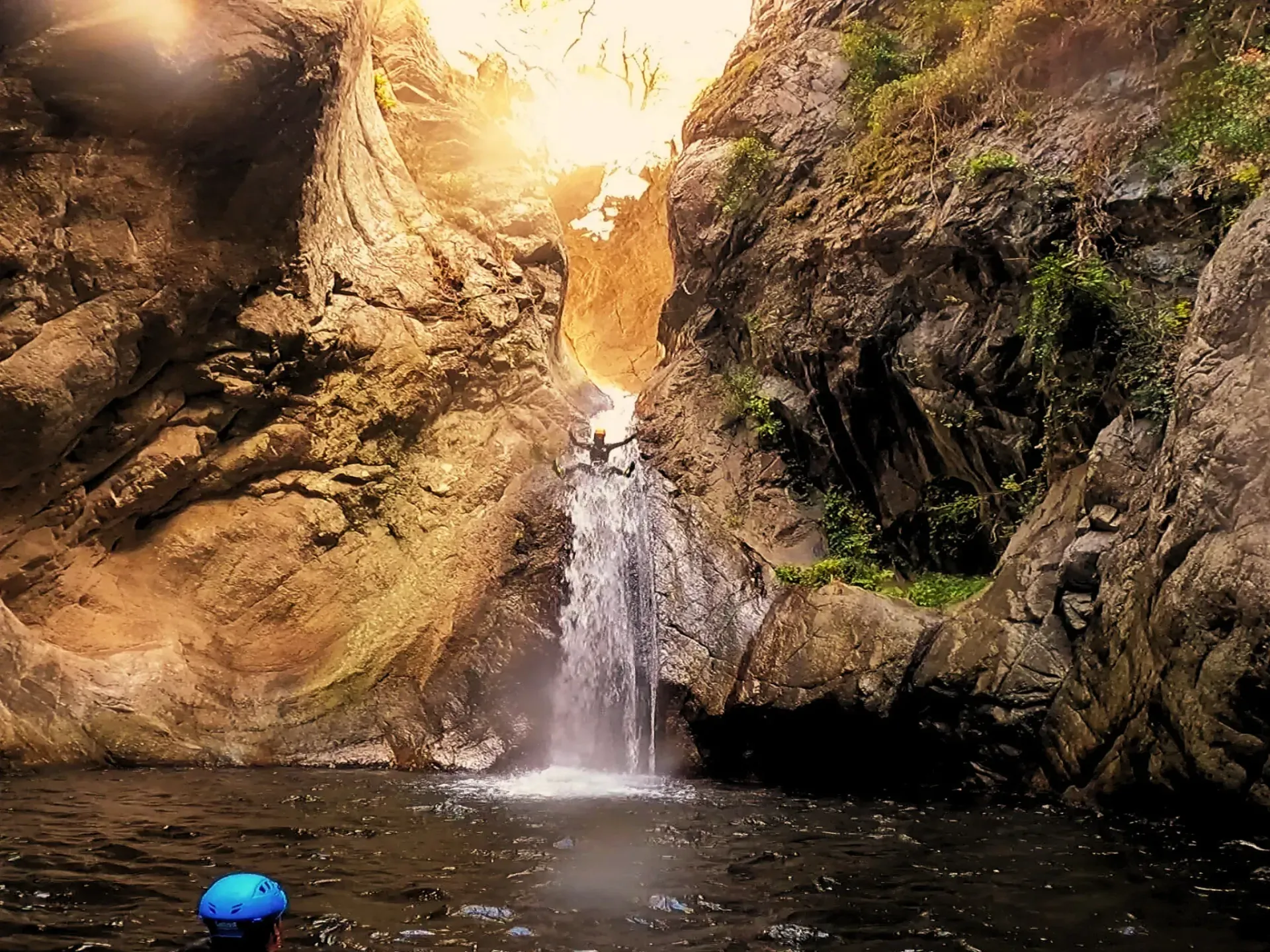 Un hombre con un casco azul está parado frente a una cascada.