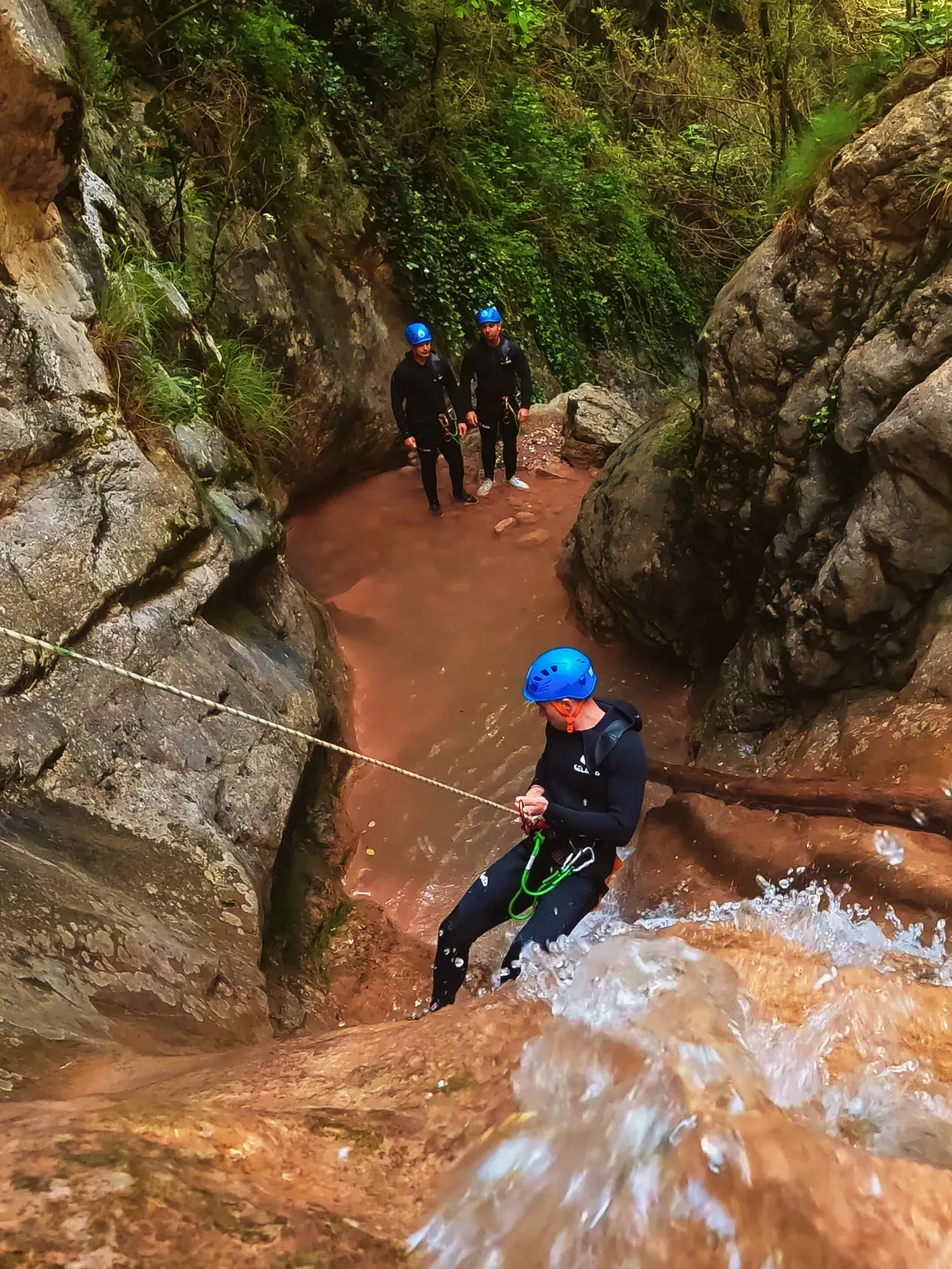 Un hombre baja por una cuerda por una cascada en un cañón.