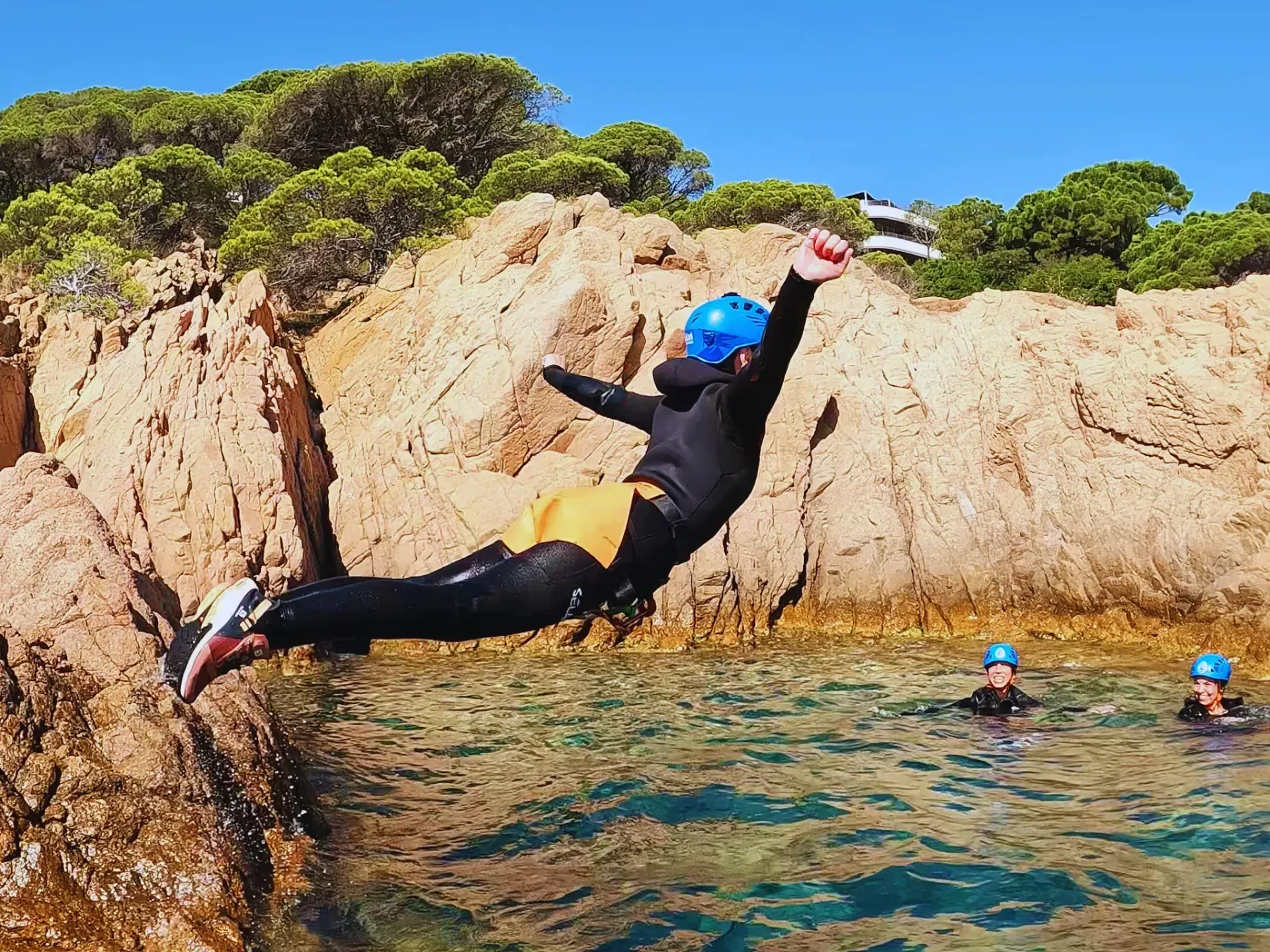 Una persona está saltando desde una roca al agua.