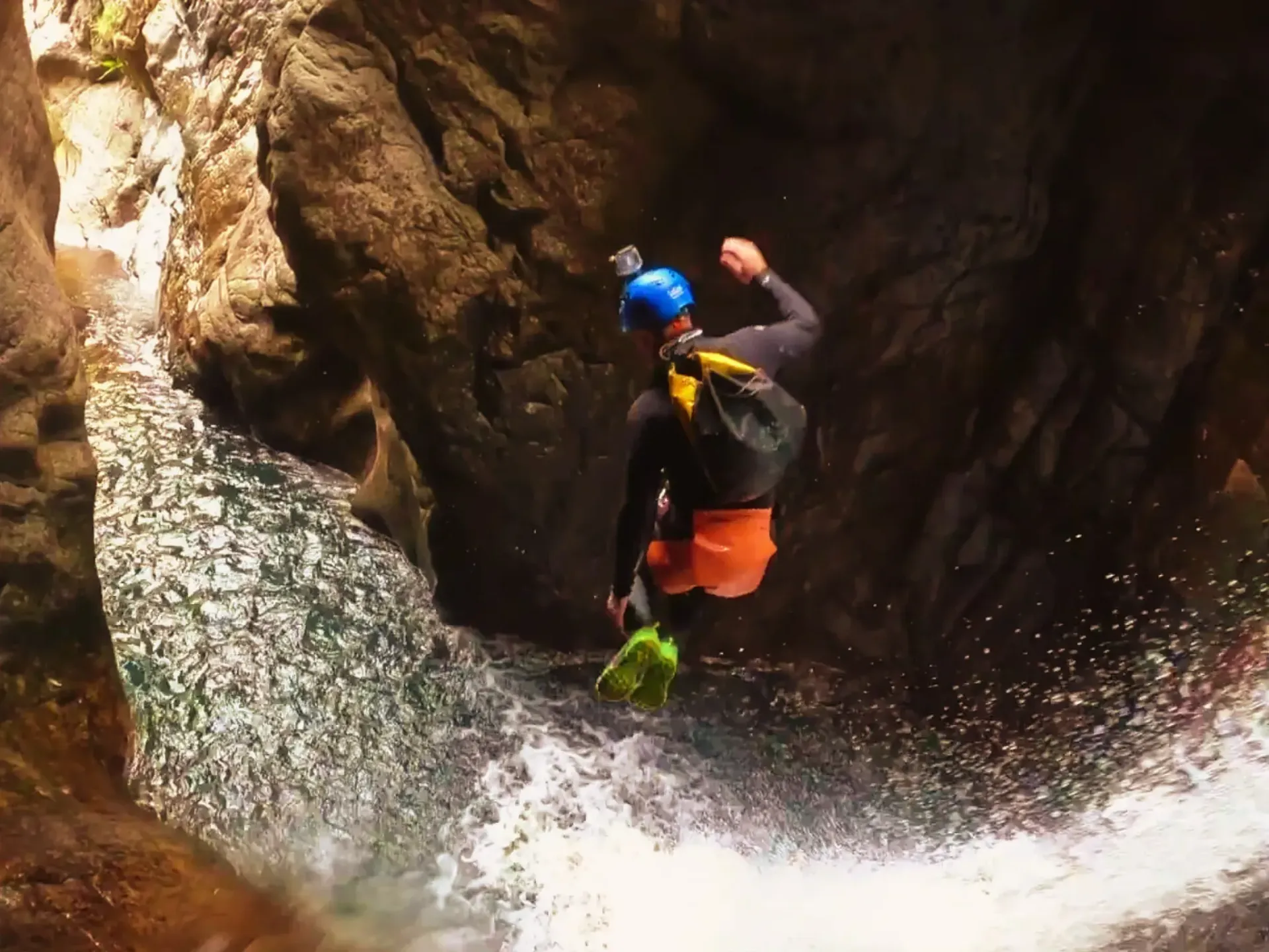 Un hombre está saltando sobre una cascada en un cañón.