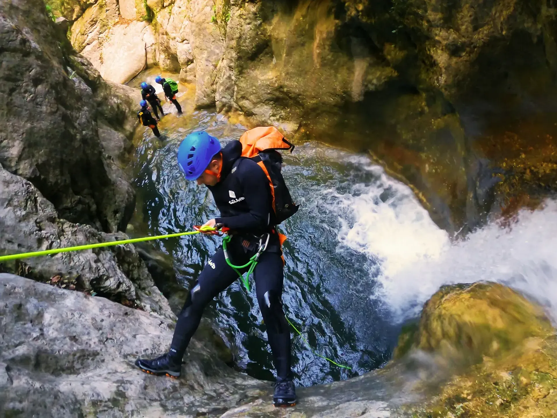 Un hombre está bajando por una cascada con una cuerda.