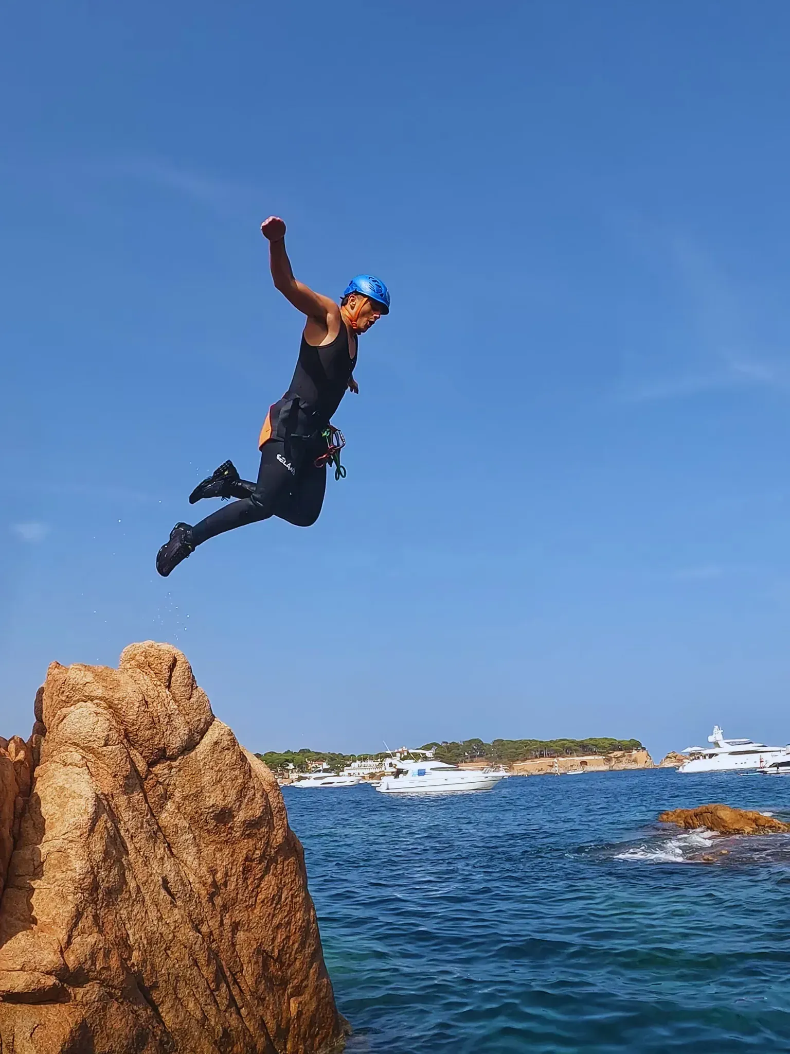 Una persona está saltando desde una roca al océano.