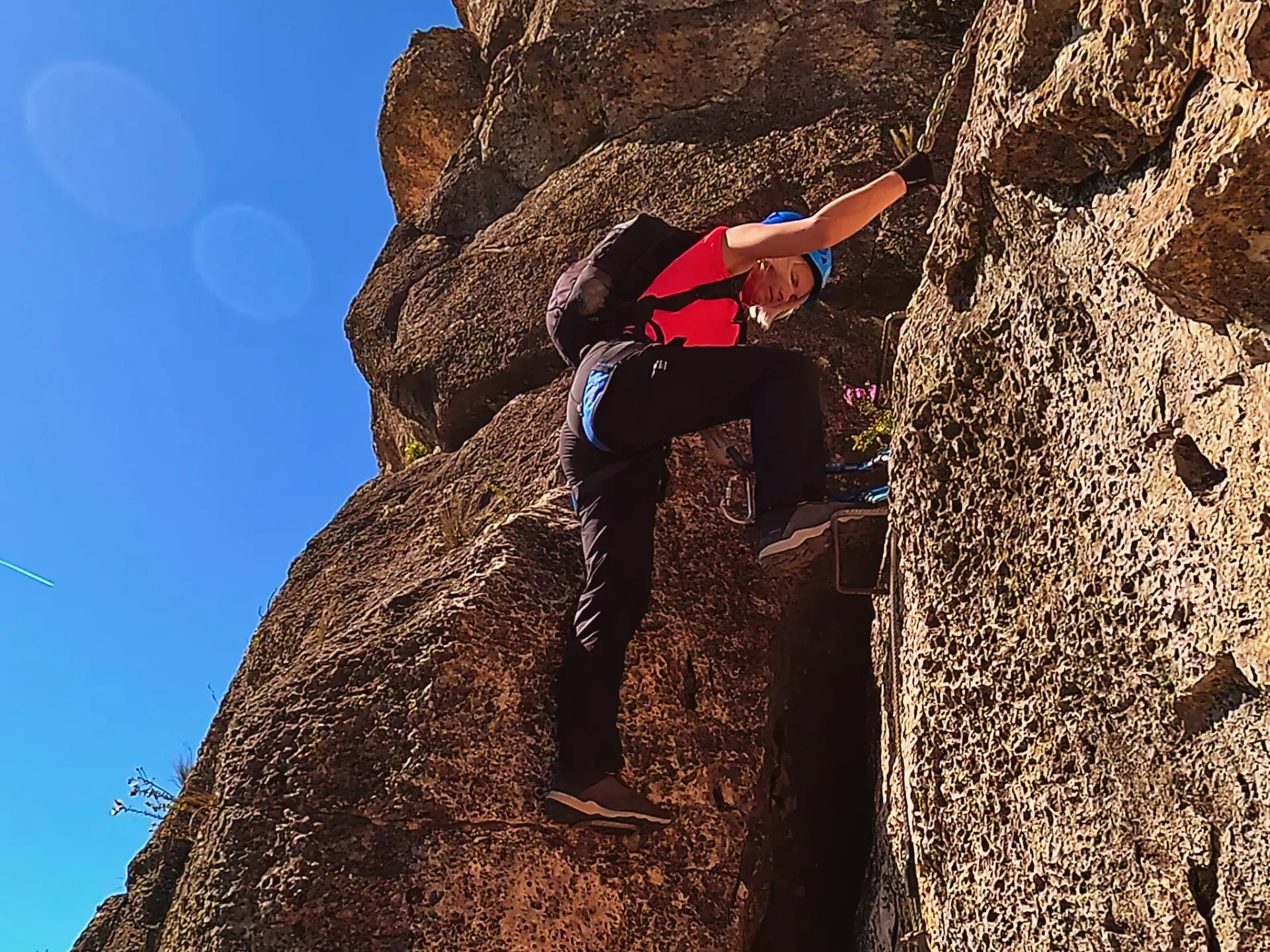 Un hombre está escalando una pared de roca en un día soleado.