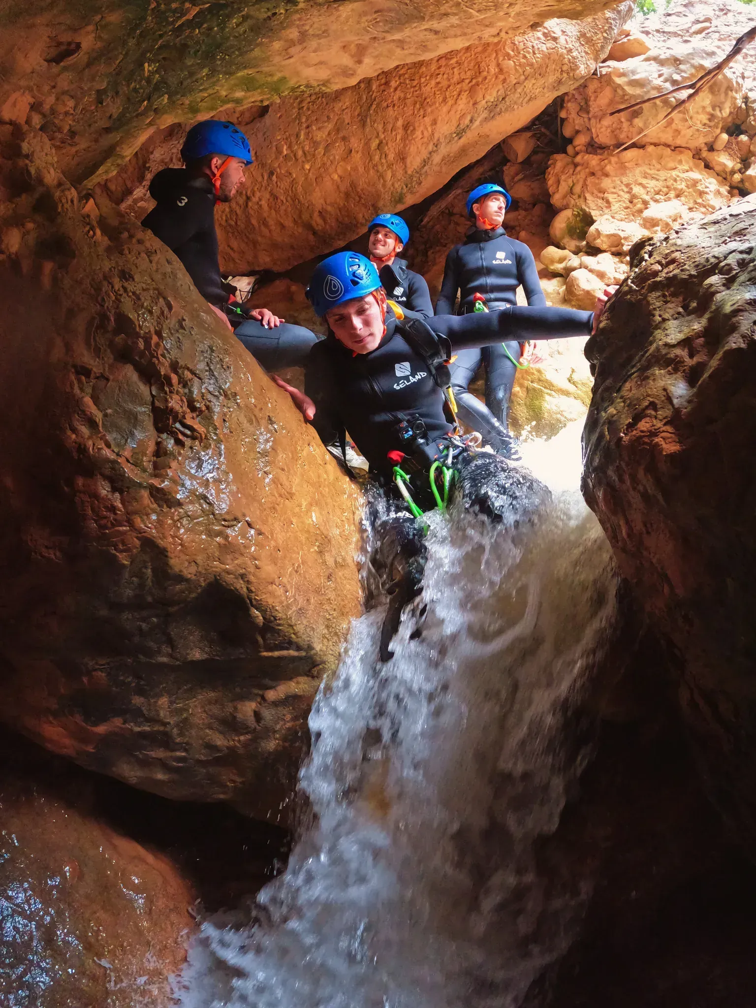 Un grupo de personas baja por una cascada en una cueva.