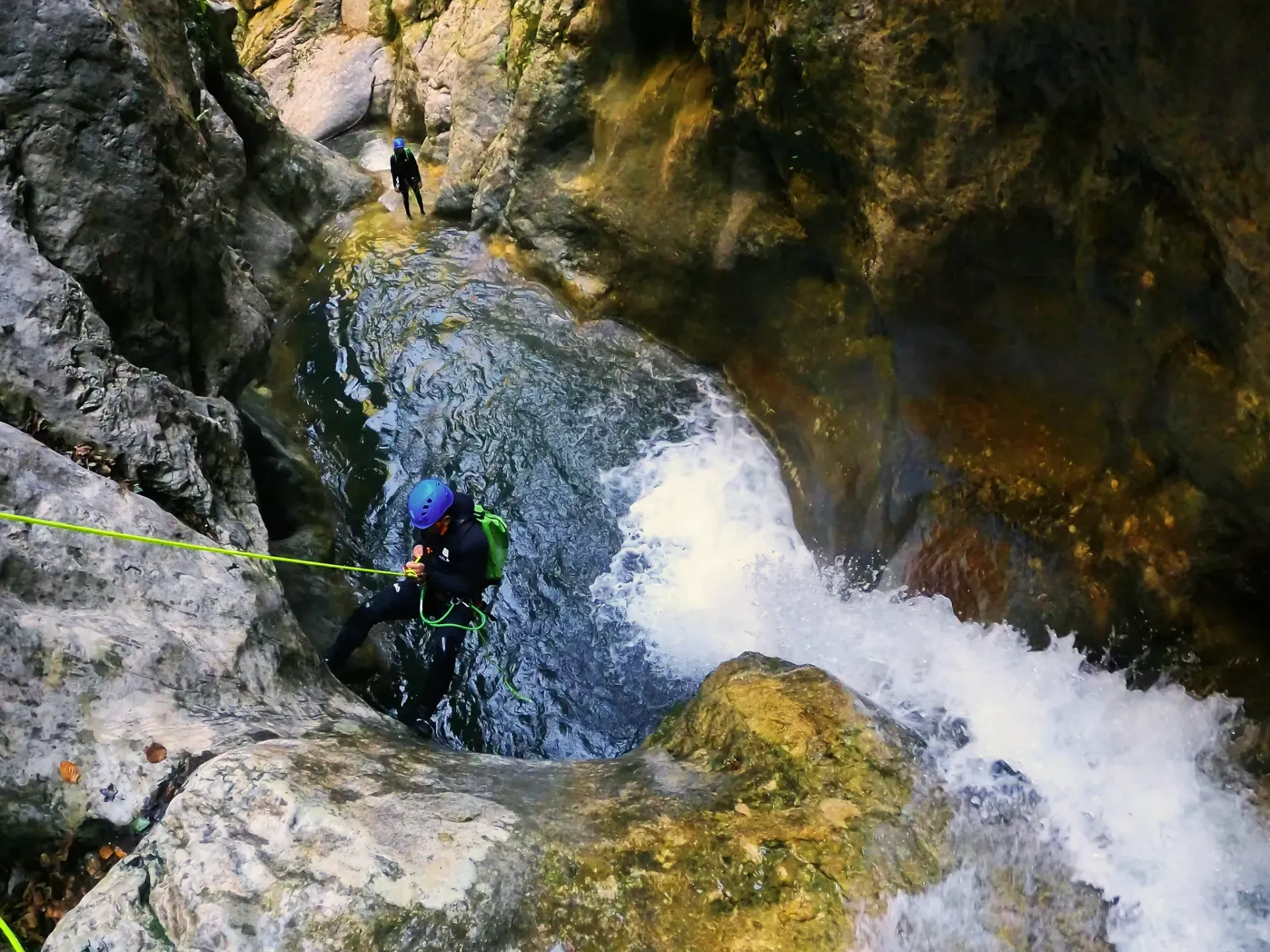 Una persona está bajando por una cascada con una cuerda.
