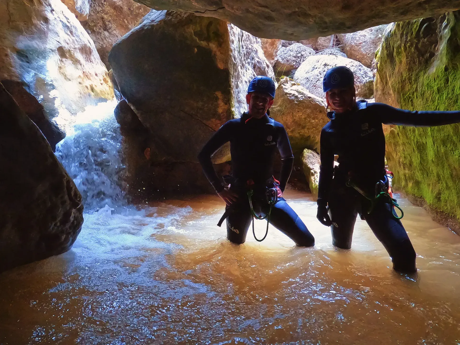 Dos personas están paradas en una cueva en el agua.
