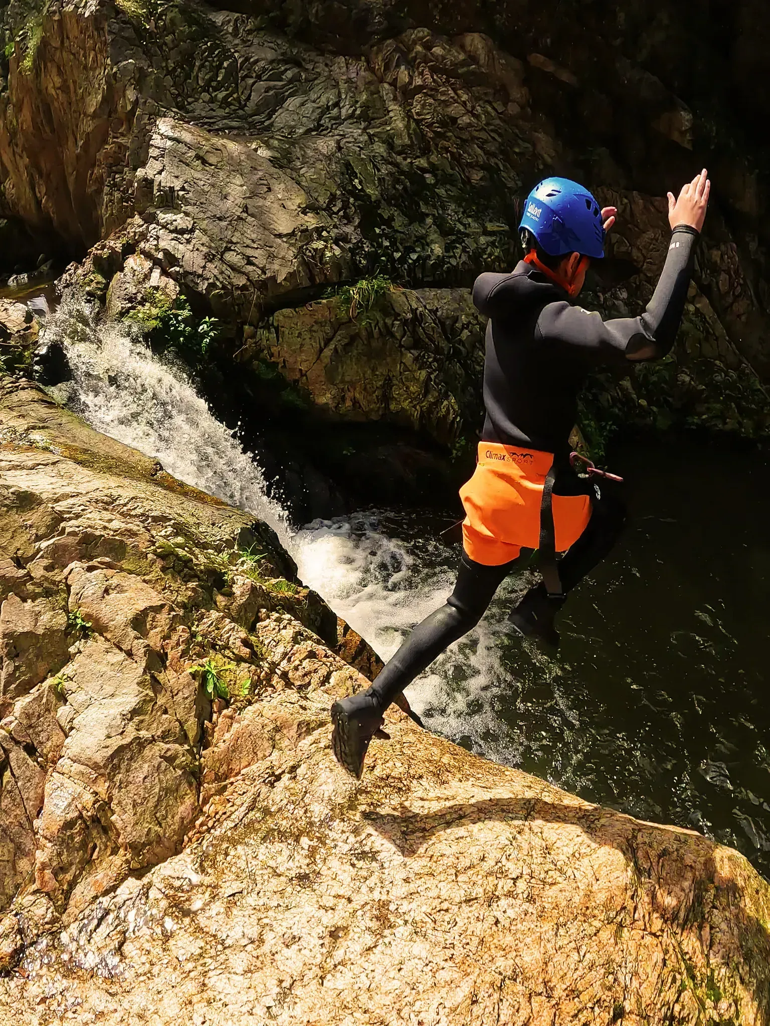 Un hombre con un casco azul está saltando a un río.