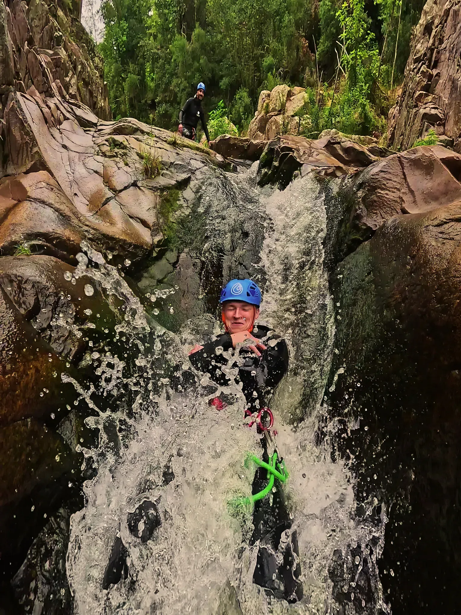 Una persona está bajando por una cascada con una cuerda.